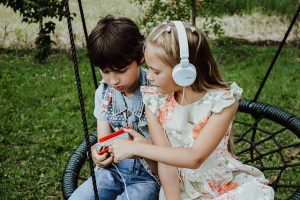 deux enfants sur une balançoire nid d'oiseau qui écoute de la musique